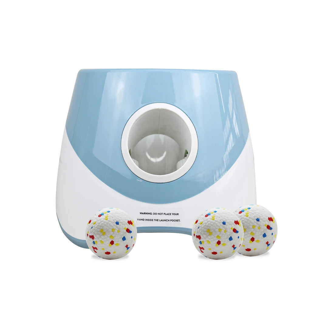 Blue and white device with launch pocket for dogs and colorful balls on a white background

