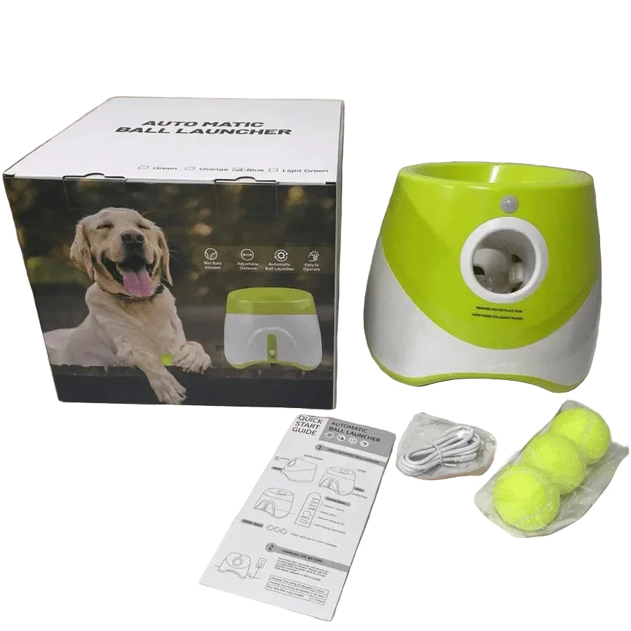 Green and white automatic ball launcher with packaging, manual, and tennis balls on a white background

