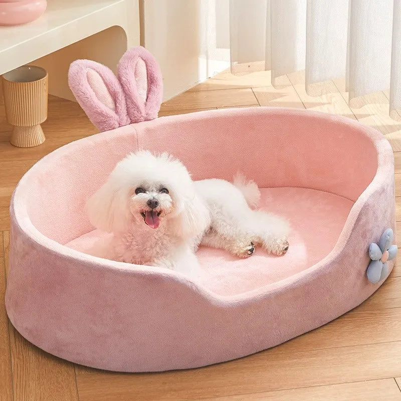 White dog lying on a pink pet bed with bunny ears in a bright room.

